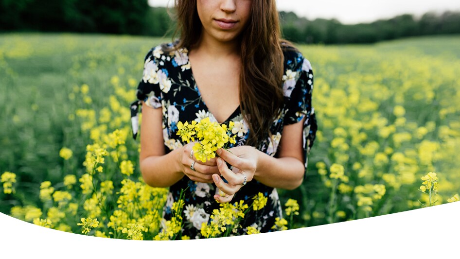Kvinnan i en blomfält som tittar ner och plockar blommor